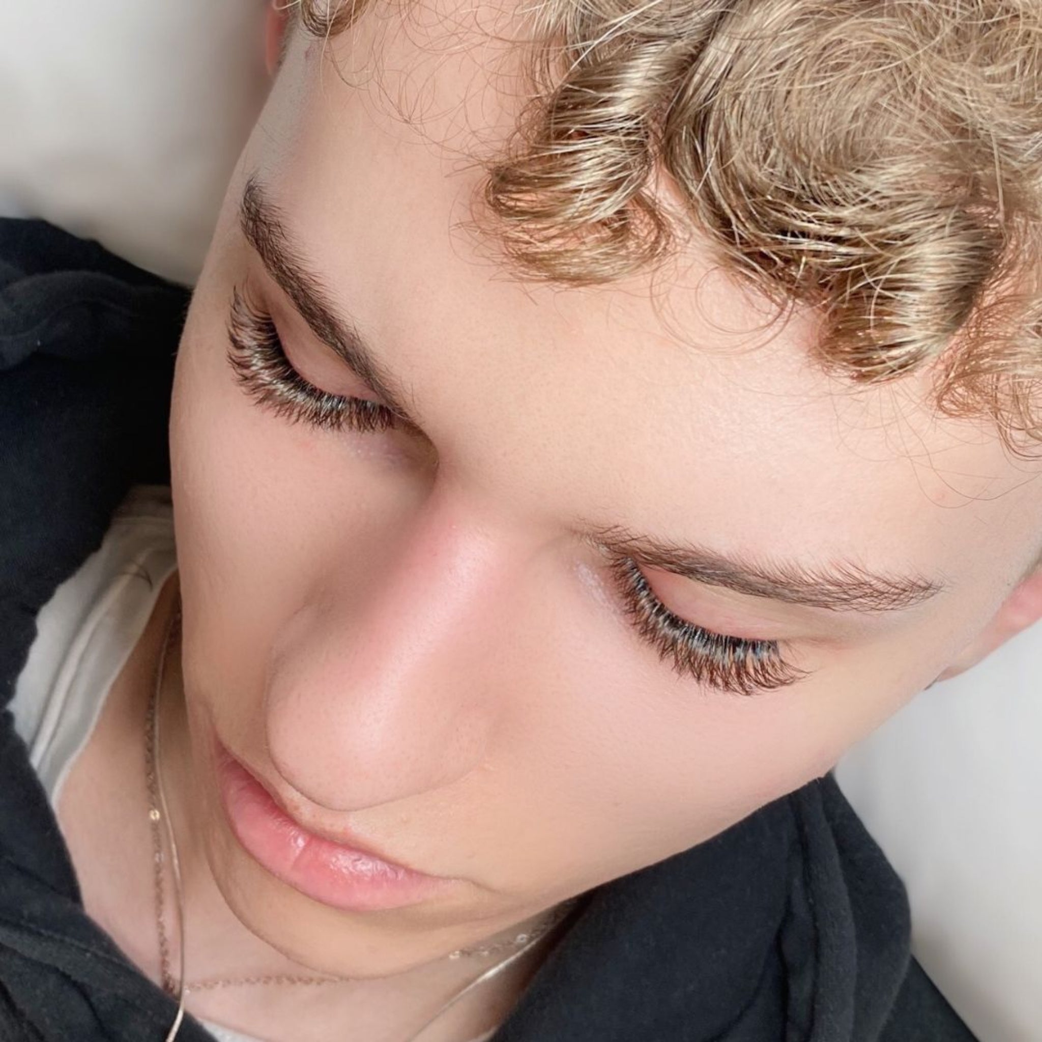 Eyelash Excellence Chocolate Brown YY Lashes treatment close-up shot showing model with eyes closed and full set of chocolate brown YY lash extensions applied from overhead angle with warm brown lash colour and natural brow texture clearly visible