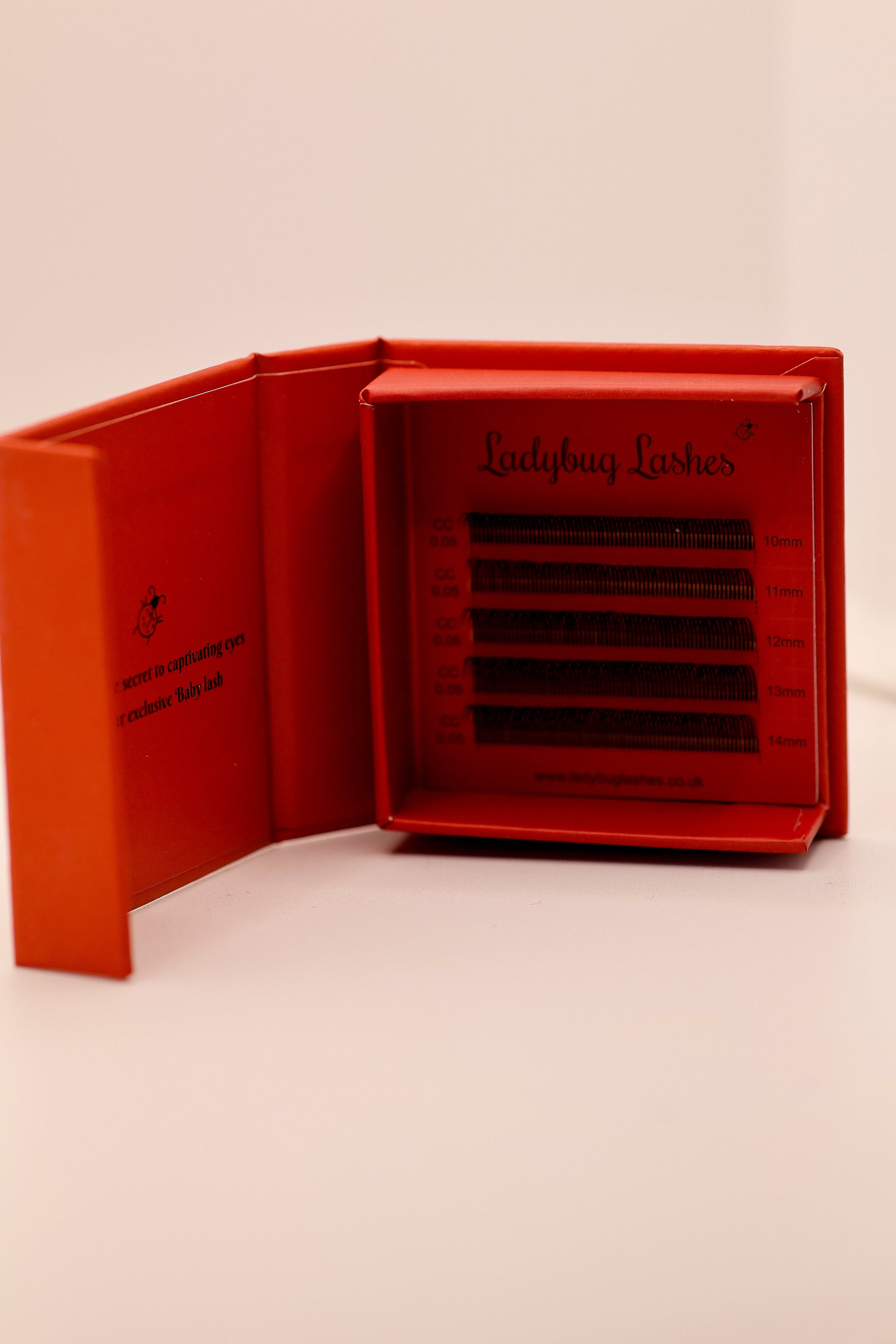 Ladybug Lashes classic lash tray open in red branded box showing multiple rows of lashes with size labels on neutral background