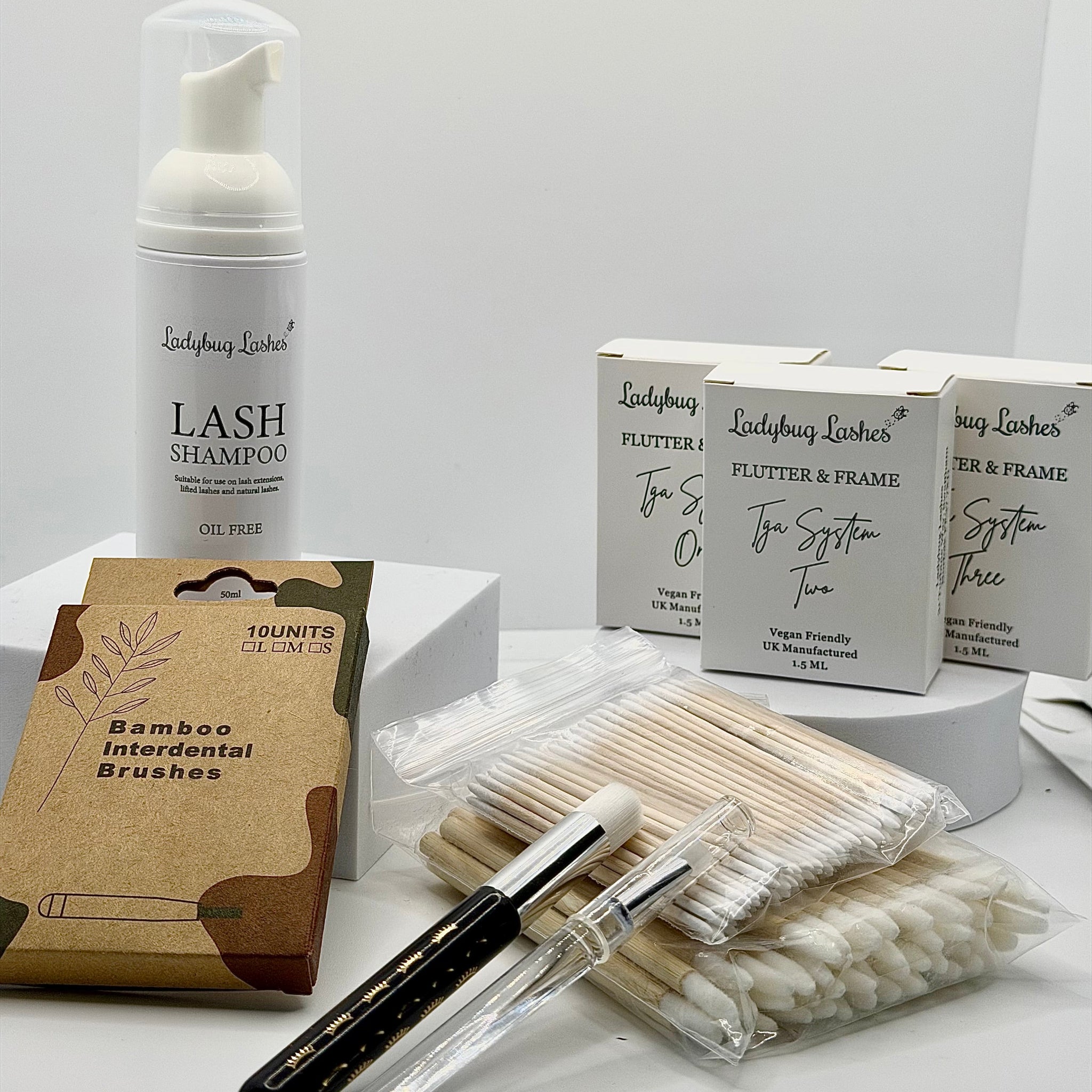 Ladybug Lashes Flutter and Frame TGA System Brow Lamination Sachet Kit flatlay showing Ladybug Lashes Lash Shampoo 50ml foam pump, three Flutter and Frame TGA System sachet boxes One Two and Three, bamboo interdental brushes pack, cotton buds and microfibre brushes on white background