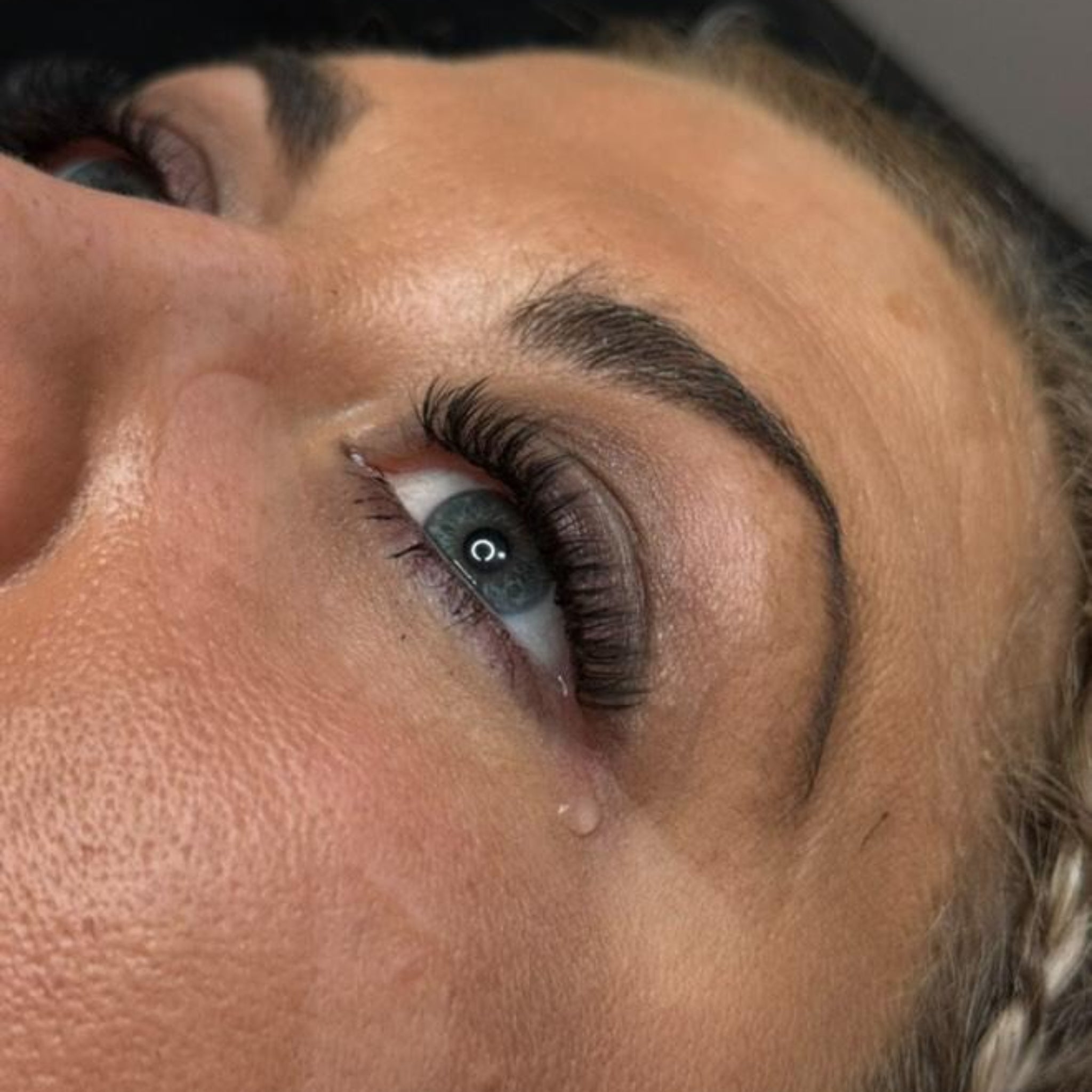 12. Close-up of Anime Feather lash extension set on brown eye showing dramatic feather spike volume with Radiant Lashes branded card visible