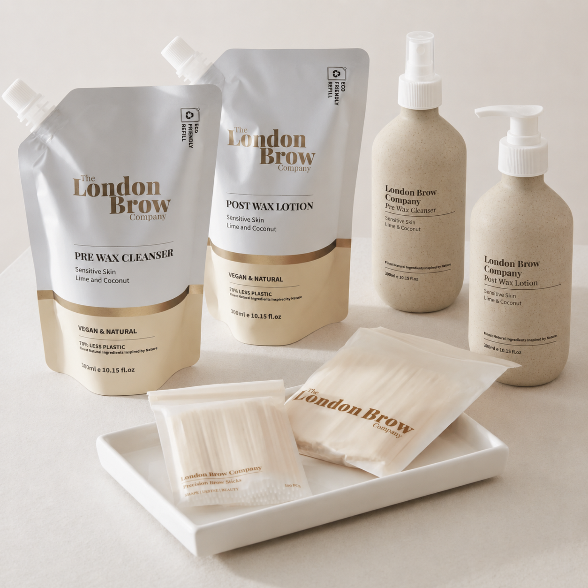 The London Brow Company Pre-Wax Cleanser & Post-Wax Lotion Set full range product shot showing eco-friendly refill pouches and 300ml pump bottles for Pre Wax Cleanser and Post Wax Lotion alongside London Brow Company precision brow sticks on white tray from front angle highlighting Vegan & Natural and 70% Less Plastic credentials
