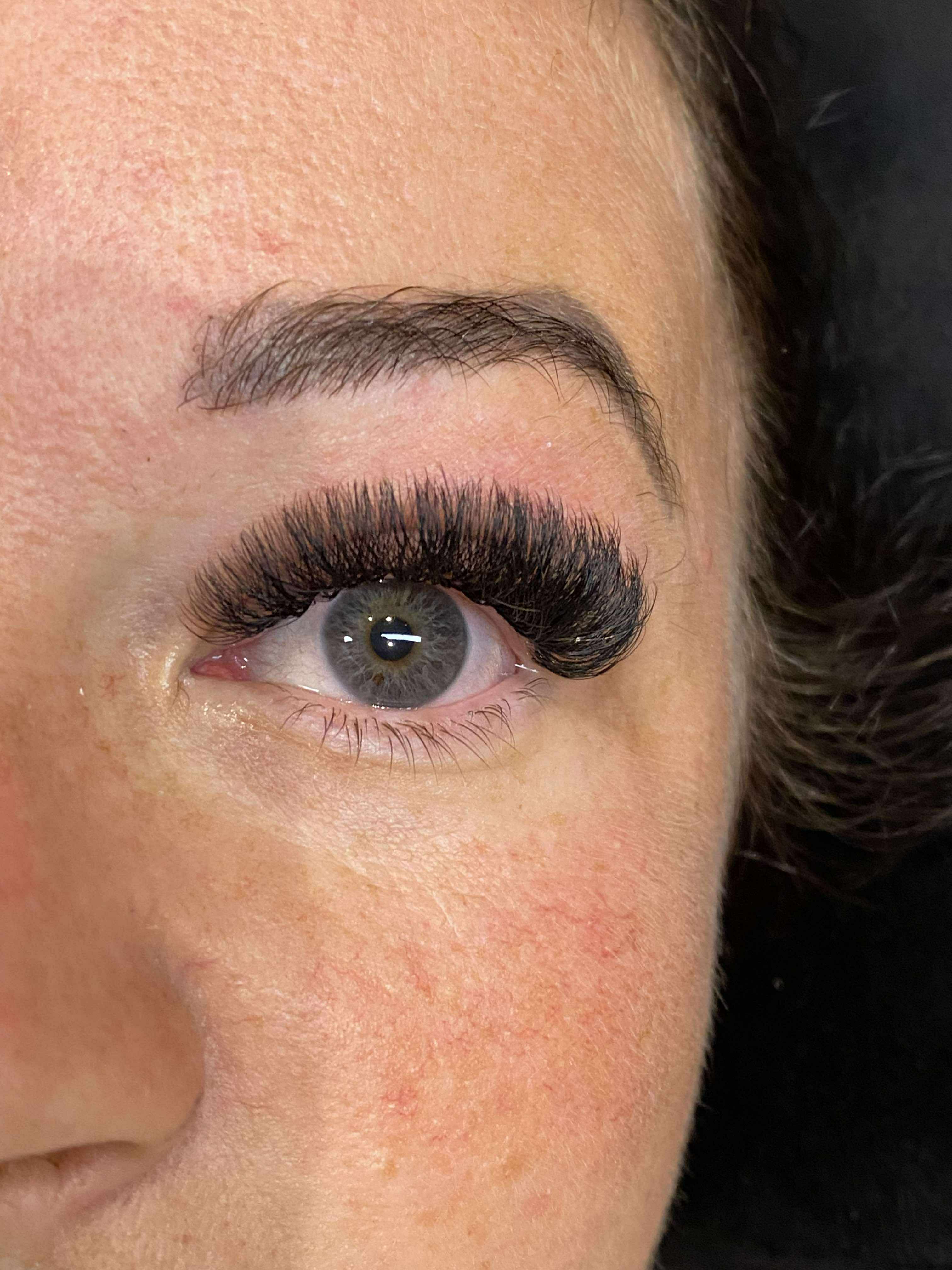 Close-up of a person's eye with false eyelashes on a dark background
