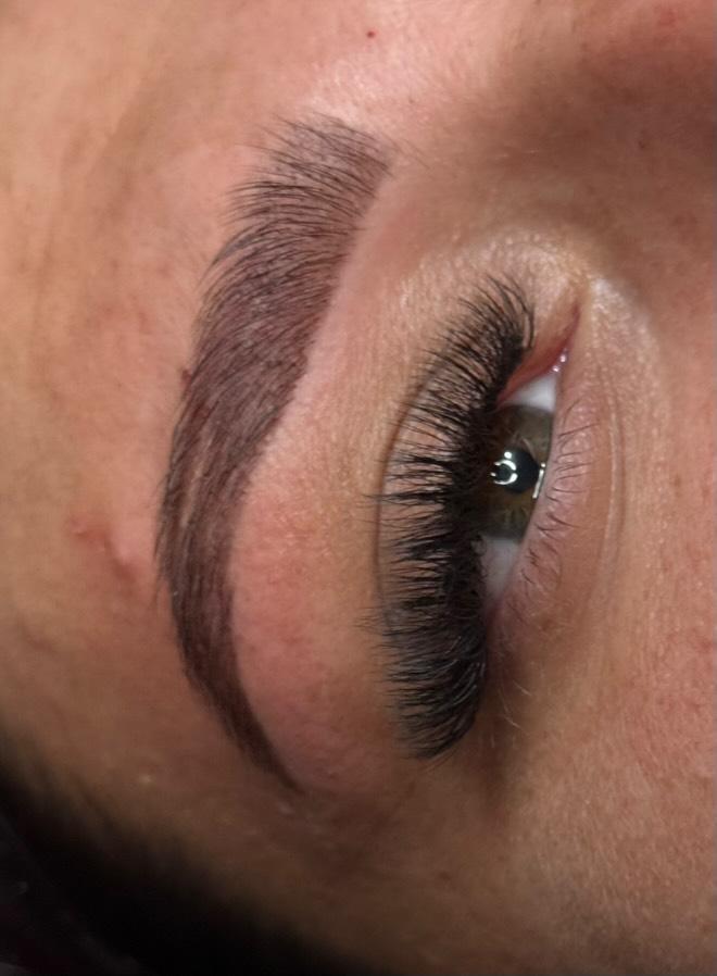 Close-up of an eye with long, dark eyelashes and a well-groomed eyebrow.
