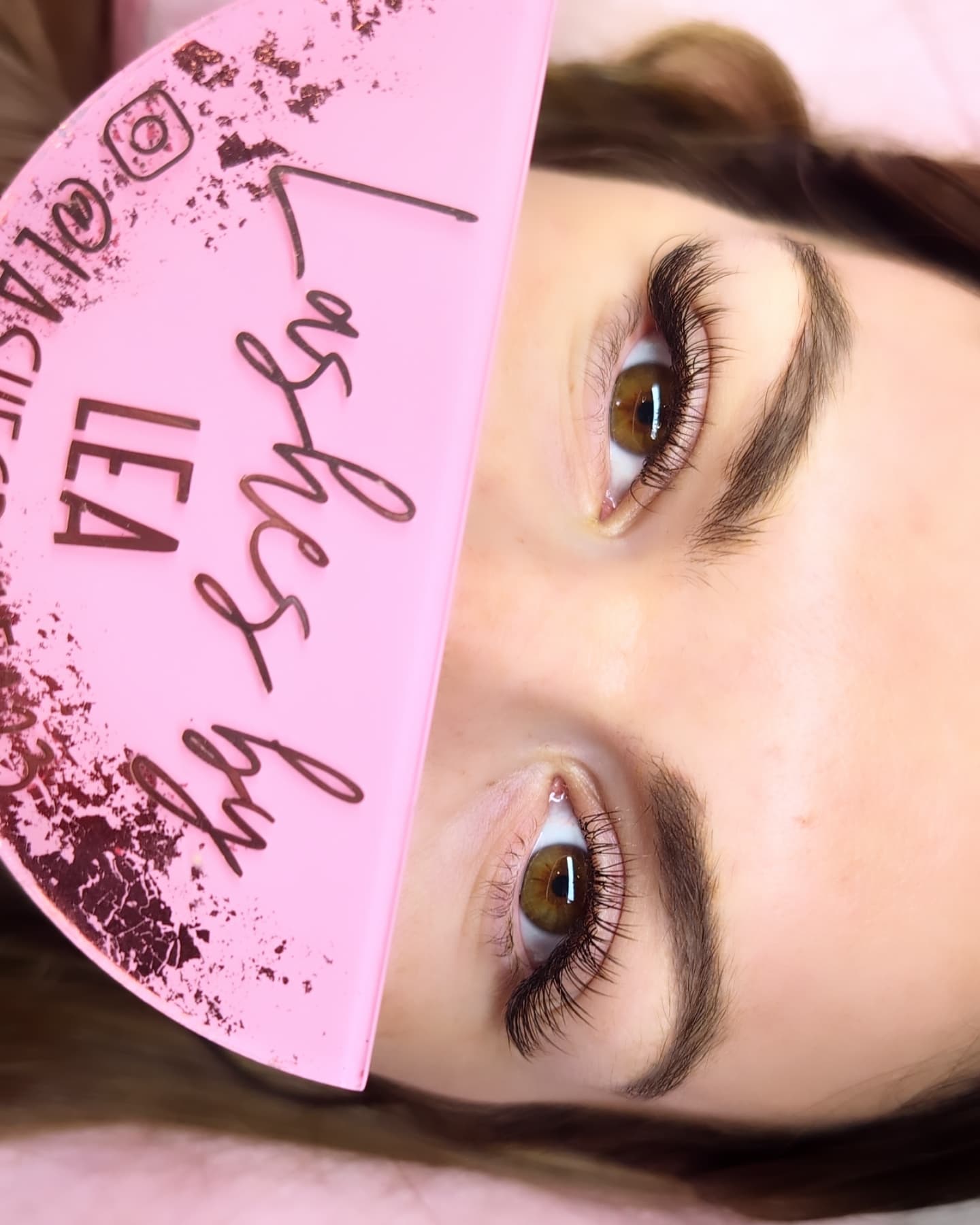Close-up of a person's eyes with a pink makeup product in the foreground.