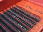Set of false eyelashes on an red tray with 'Ladybug Lashes' branding.