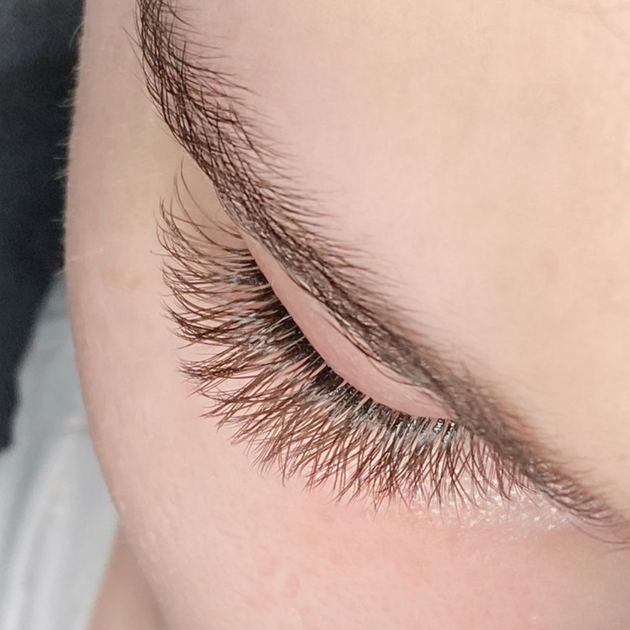 Eyelash Excellence Chocolate Brown YY Lashes extreme close-up result shot showing finished set of chocolate brown YY lash extensions on closed eye from diagonal side angle with warm brown lash colour natural curl and fine individual strand separation clearly visible against fair skin