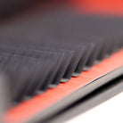 Extreme macro side-angle close-up of L curl lash extensions on red Ladybug Lashes tray showing flat base and distinctive L-shaped curl structure