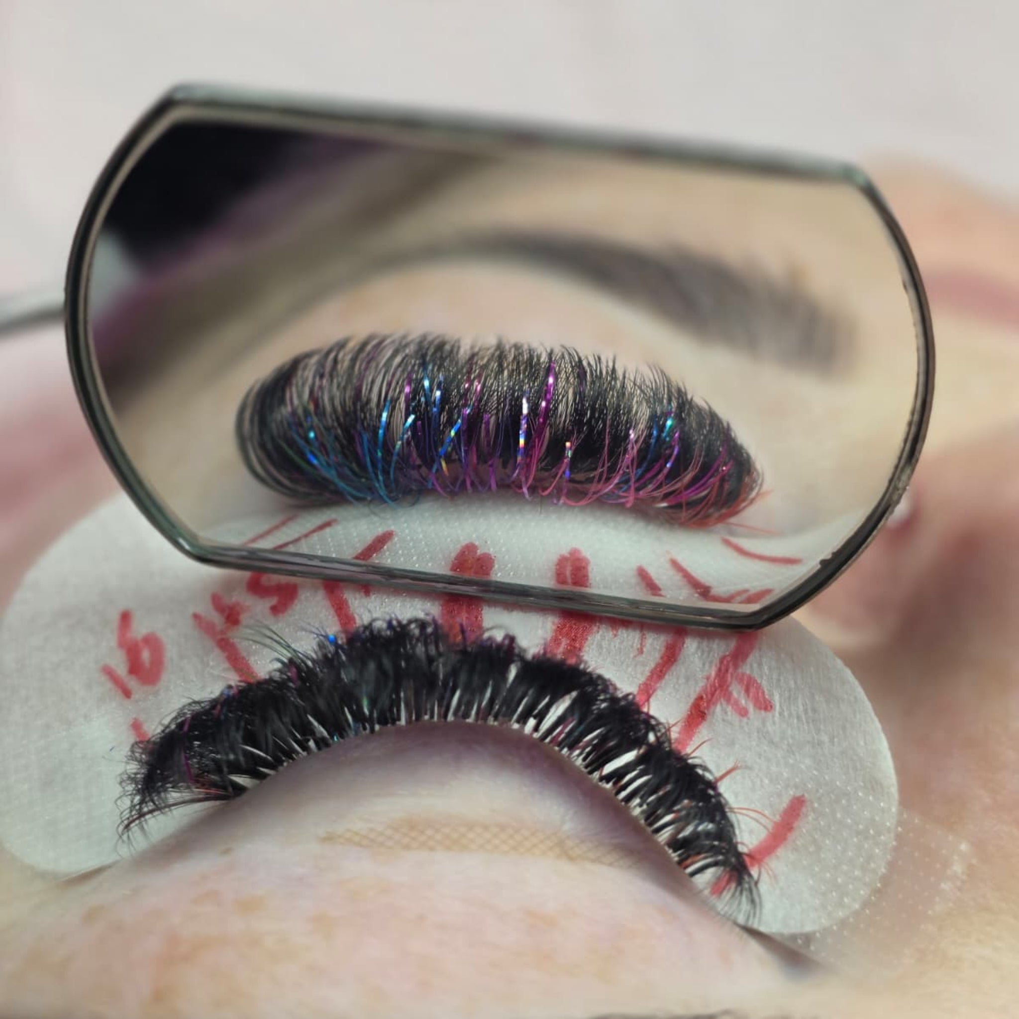 Completed Ladybug Lashes YY and Tinsel lash set on blue-grey eye showing full volume with iridescent blue tinsel fibres from front angle