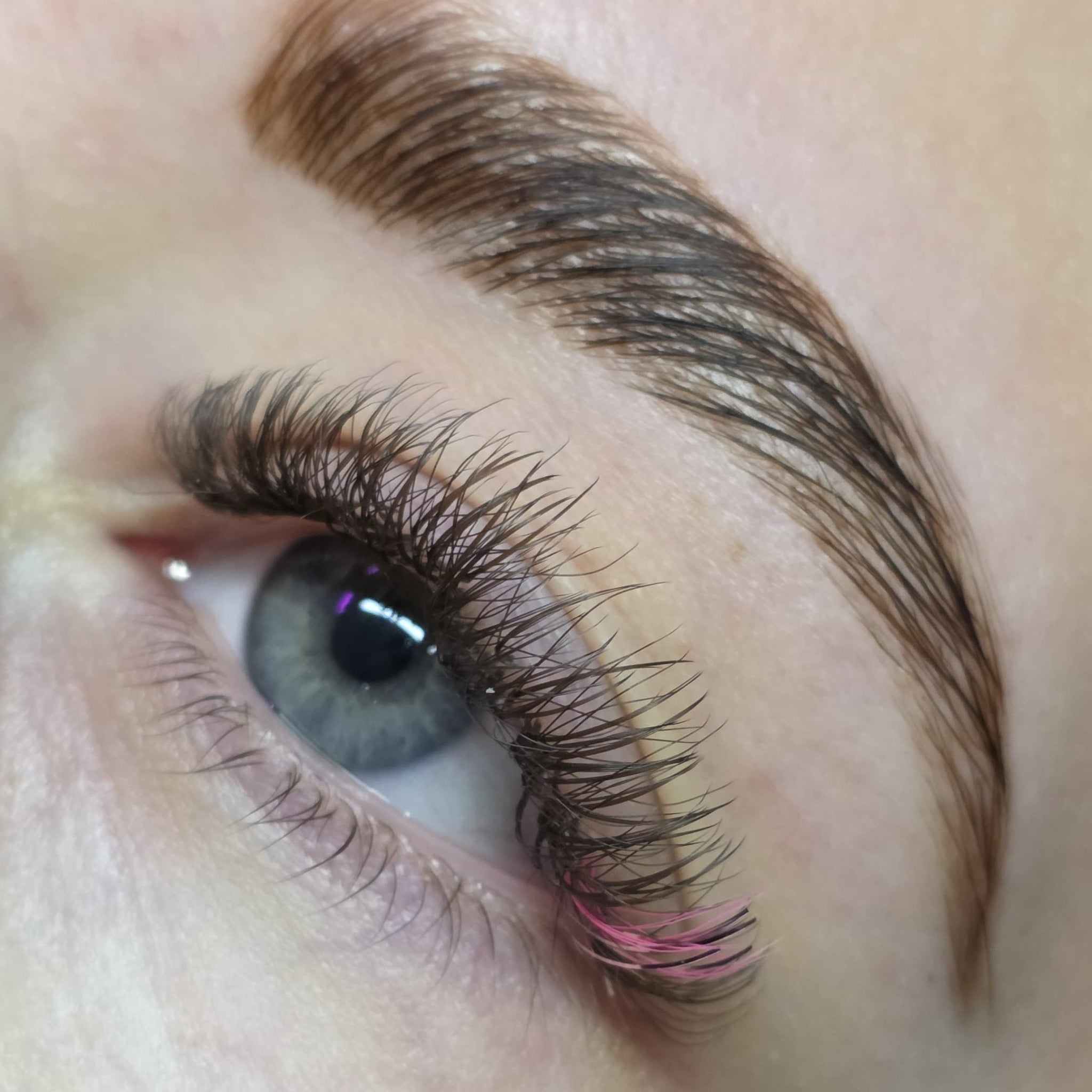 Completed Ladybug Lashes YY and Tinsel lash set on blue eye showing dense volume with holographic blue tinsel fibres from side angle