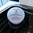 Cream remover container on a reflective surface with a blurred background