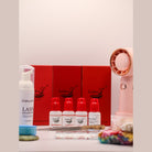 Ladybug Lashes Silver Lash Starter Kit contents displayed on a white surface showing three red Ladybug Lashes lash tray boxes, white foam lash shampoo pump bottle, four white and red Ladybug Lashes bottles labelled Gel Remover, SuperBonder, pH Balancer and Wildflower adhesive, blue gel tape roll, jade stone, tweezers, bamboo applicator wands, coloured mascara spoolies and a pink rechargeable USB mini fan