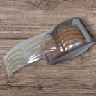 Transparent adhesive strip with brown adhesive patches on a wooden surface