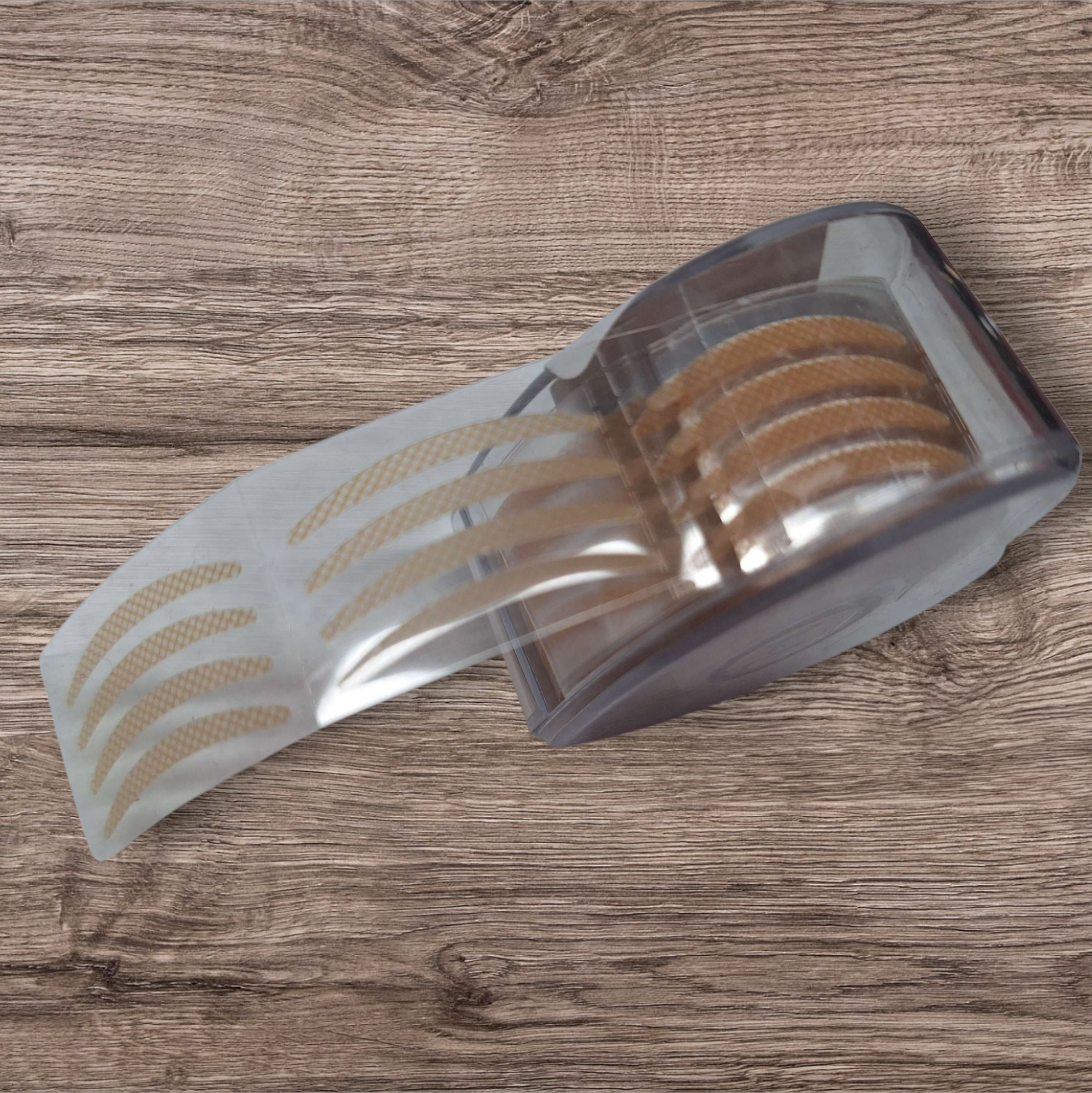 Transparent adhesive strip with brown adhesive patches on a wooden surface