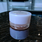Small jar with a white lid on a reflective surface