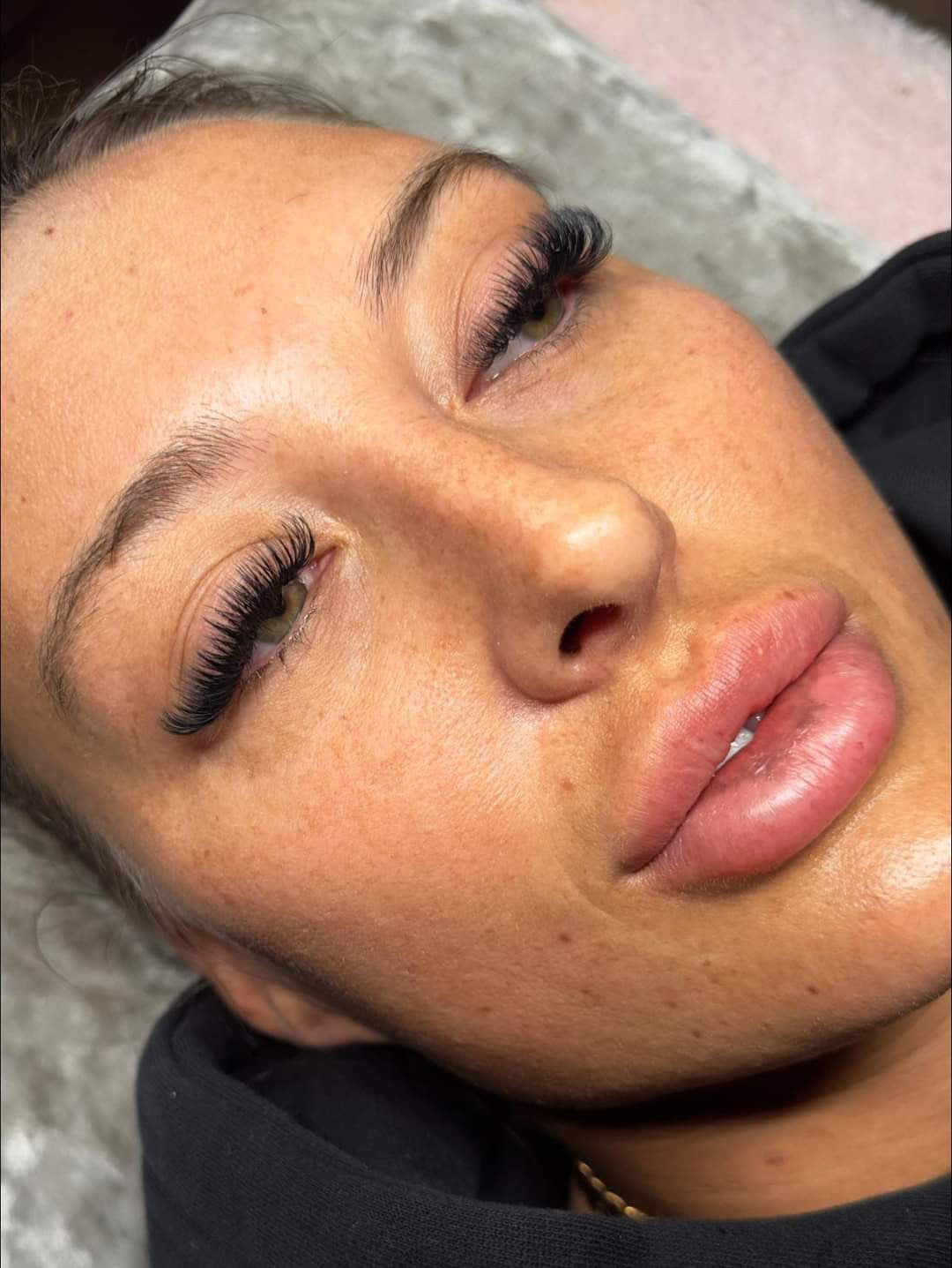 A close-up image of a person's face showcasing applied false eyelashes with a focus on the eyes and lips.