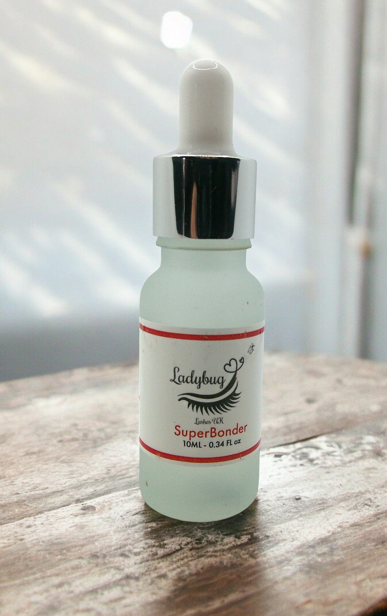 A bottle of 'Super bonder 10ml Strawberry Scented' with a dropper, labeled for eyelash extensions.