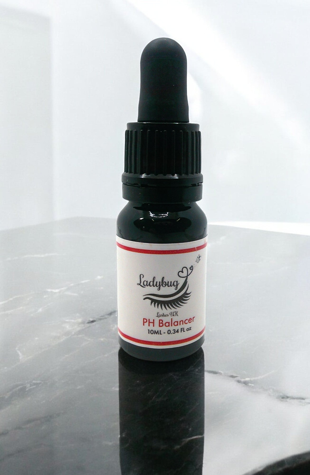 A bottle with a dropper labeled as 'pH Balancer/Primer 10ml Apple Scent' from Ladybug brand.