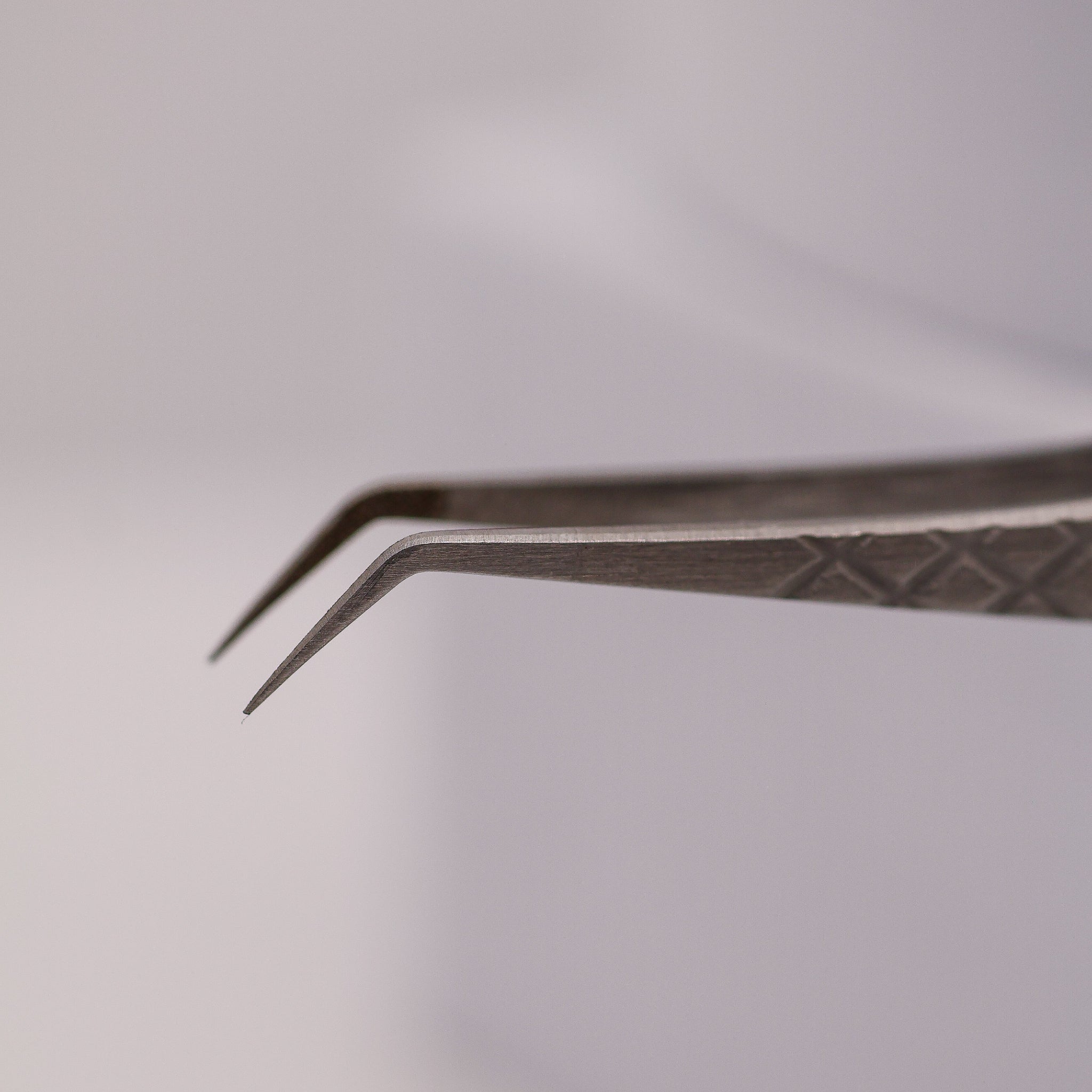 Close-up of LADYBUGLASHES Angled Volume Tweezers – silver fibre grip tip detail