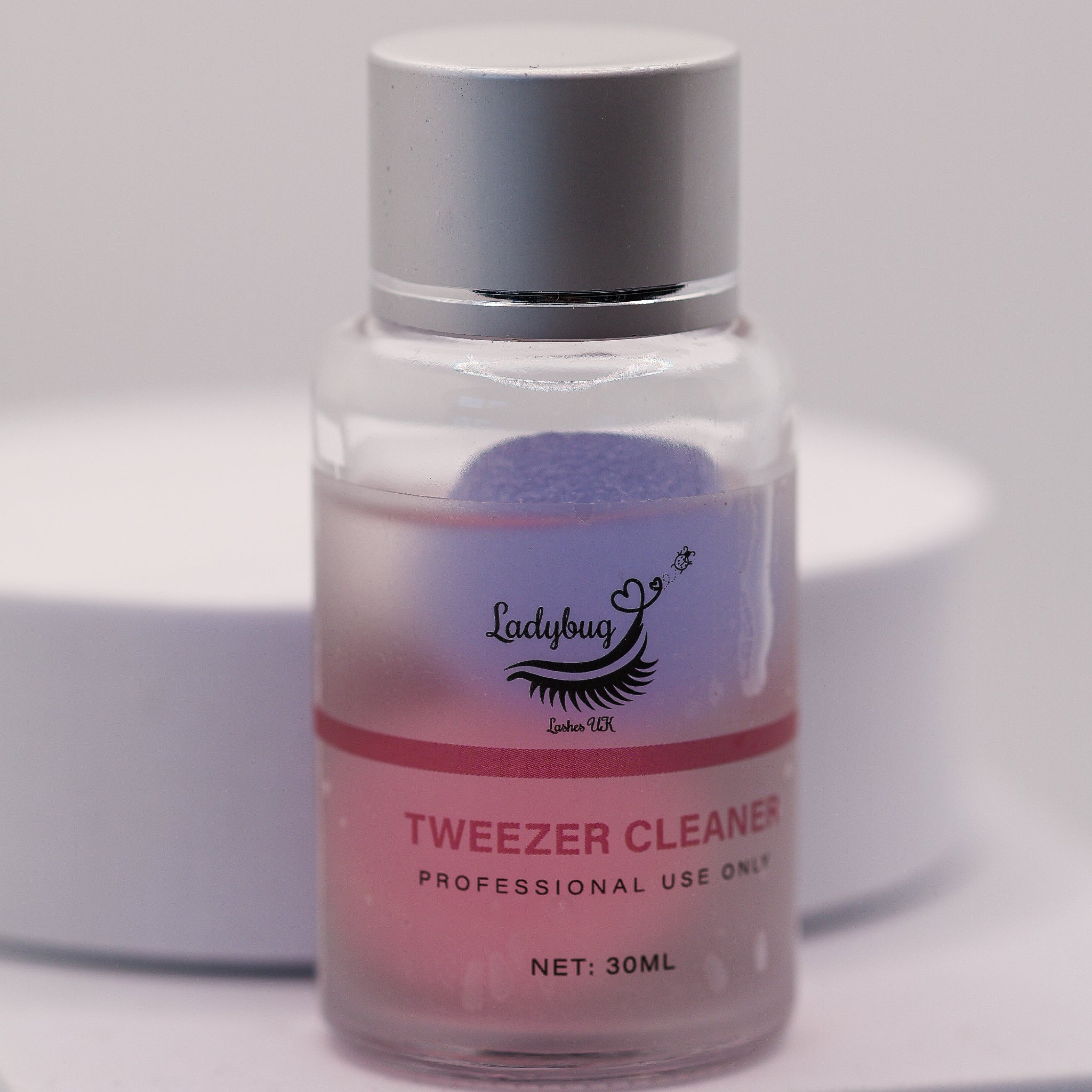 Ladybug Lashes Tweezer Cleaner 30ml product shot showing a clear glass bottle with silver cap and branded white label reading Tweezer Cleaner Professional Use Only 30ml from a front-facing angle on a white background