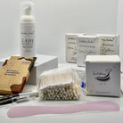 Ladybug Lashes Express Cysteamine Brow Lamination Sachet Kit flatlay showing Ladybug Lashes Lash Shampoo foam pump, three Flutter and Frame Express Cysteamine sachet boxes, Ladybug Lashes 42mm x 200m brow lamination wrap box, bamboo interdental brushes pack, cotton buds, microfibre brushes and pink silicone spatula on white background
