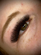 Close-up of an eye with long, dark eyelashes and a light-colored iris.