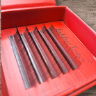 Eyelash extensions in a red box on a wooden surface