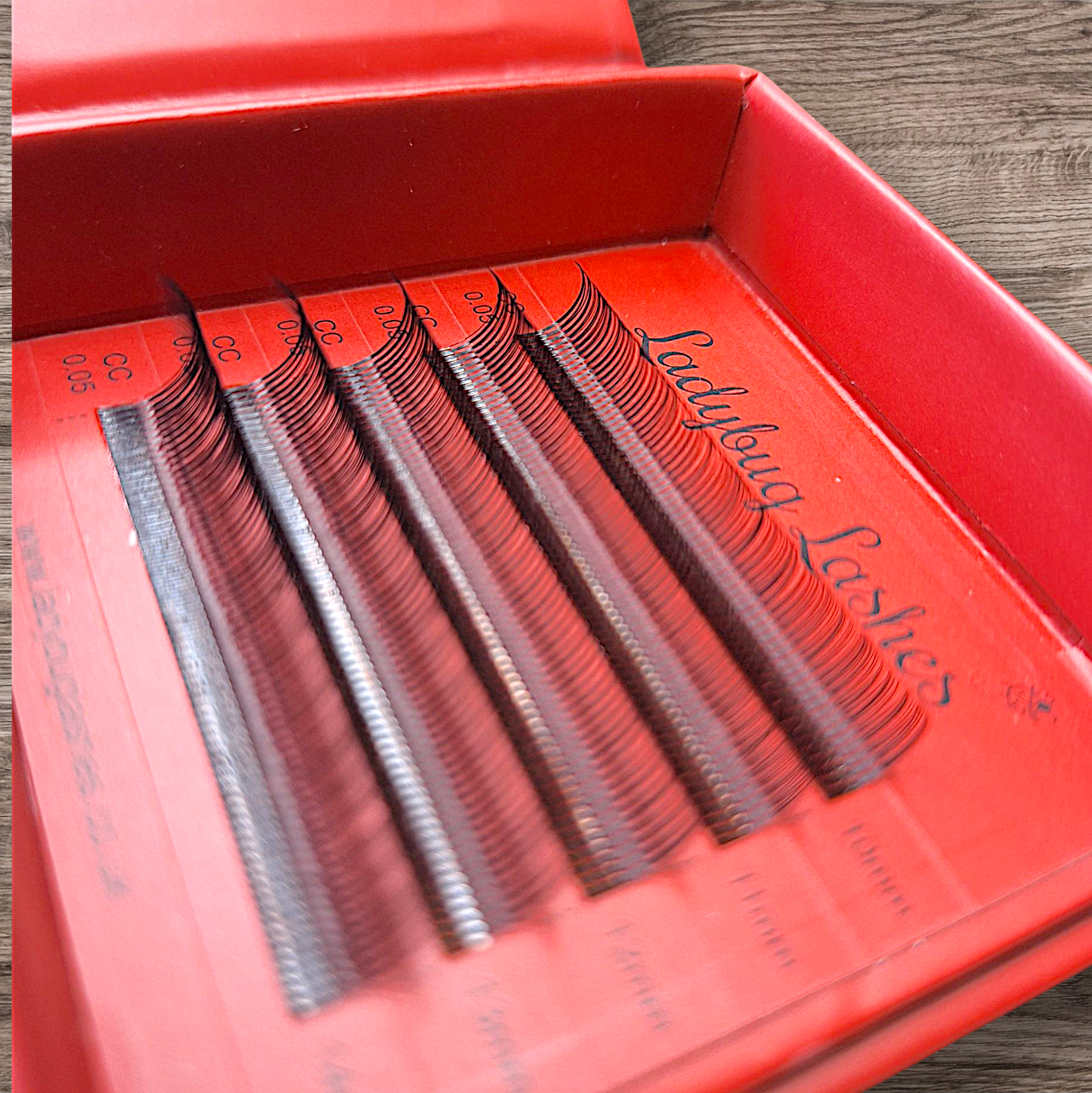 Eyelash extensions in a red box on a wooden surface