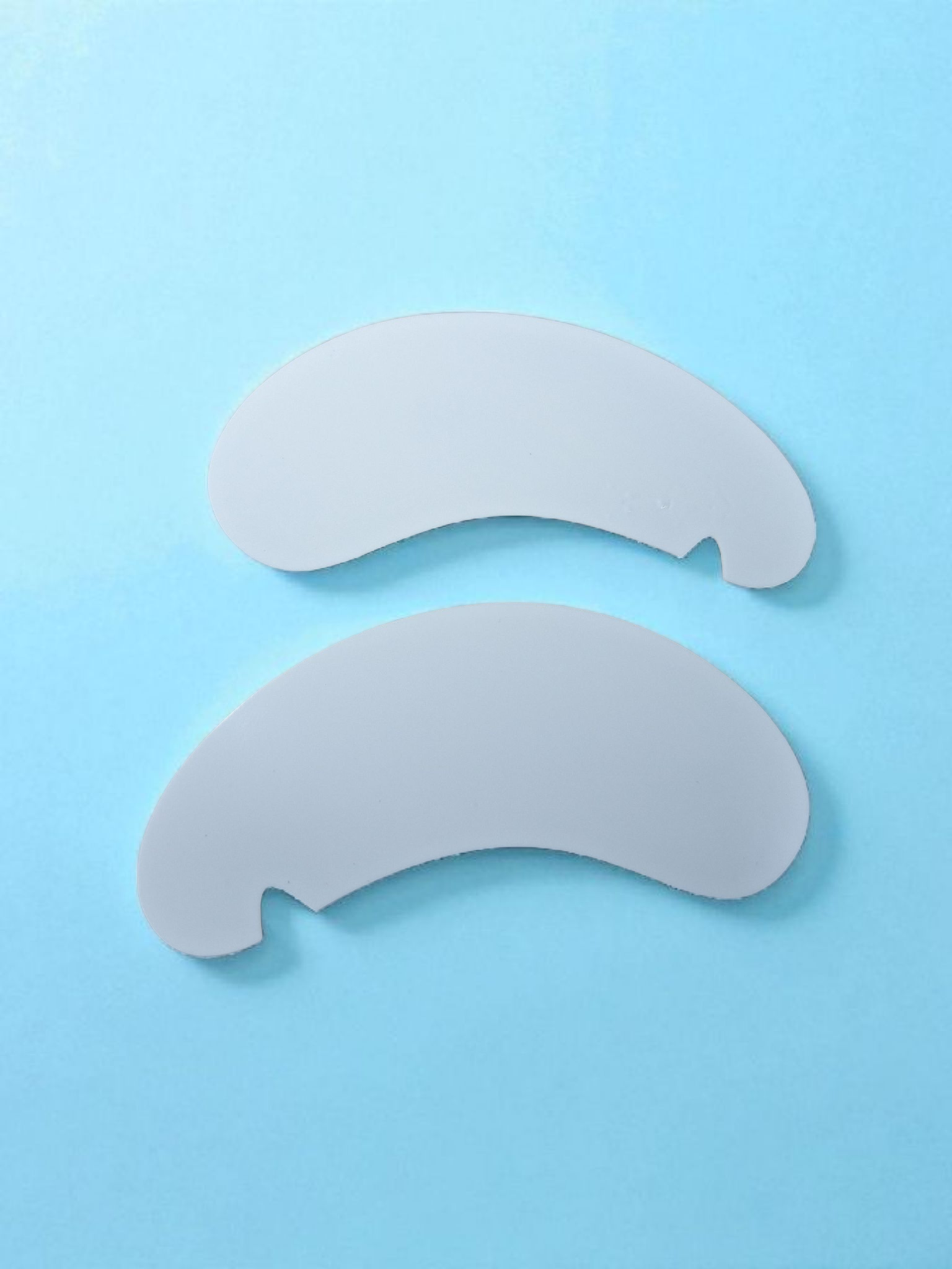 Two white eye patches on a light blue background