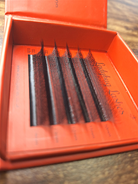 Open box of false eyelashes with visible branding on a wooden surface