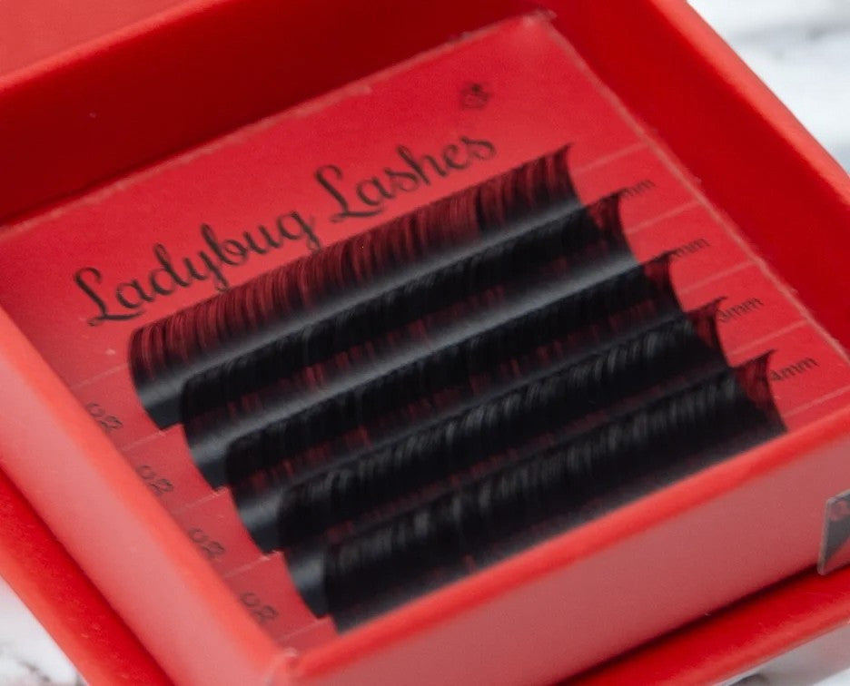 A close-up of a person's eye wearing voluminous pink false eyelashes, showcasing the product's use.