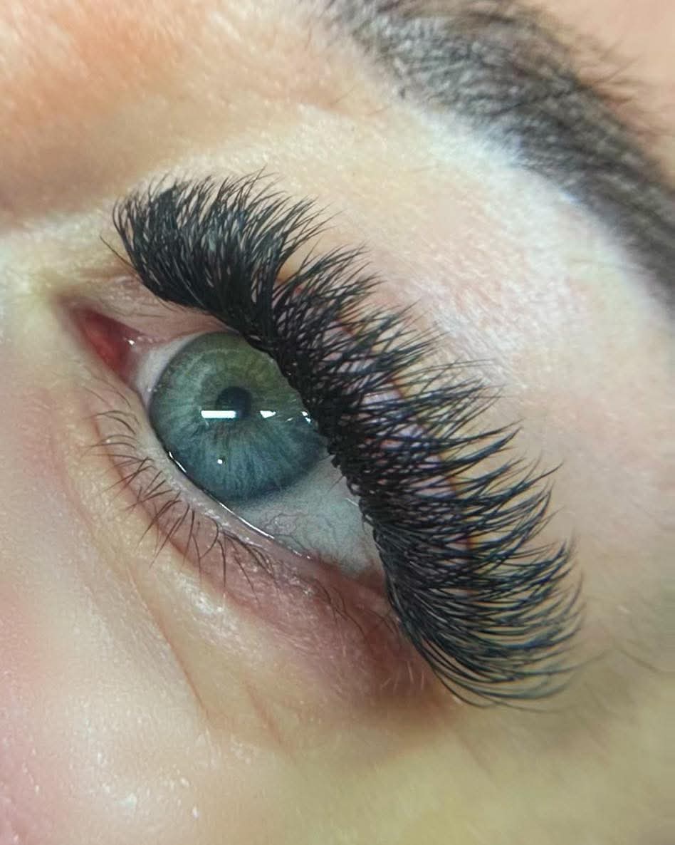 Close-up of an eye with applied false eyelashes, showcasing a single eye with extended eyelashes creating a voluminous look.