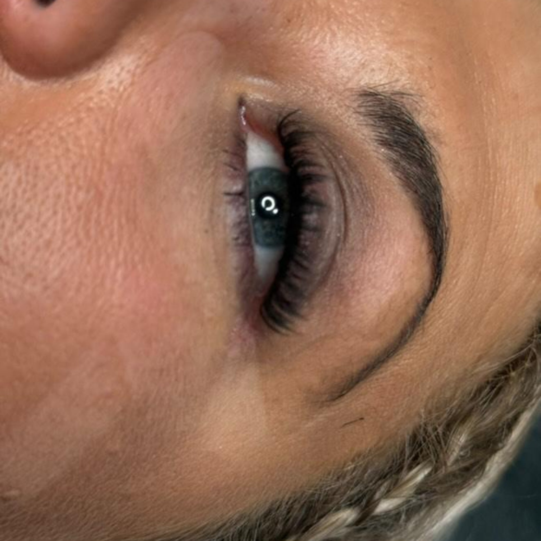 Extreme close-up side view of Anime Feather lash extension set on blue-grey eye showing dramatic feather spike definition and full dense volume short set