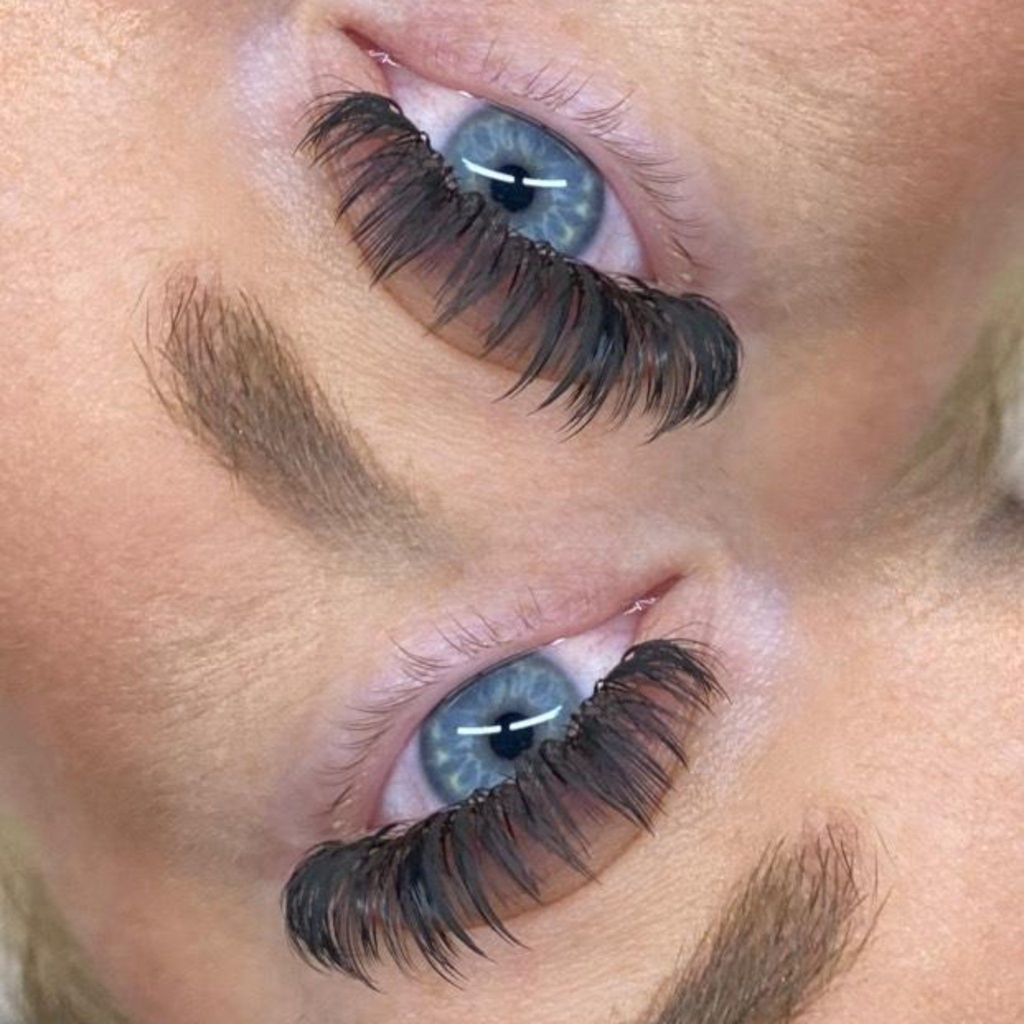 Extreme close-up side view of Anime Feather lash extension set on blue-grey eye showing dramatic feather spike definition and full dense volume