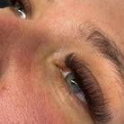 Completed brown Fairy lash extension set on blue-grey eyes showing soft wispy volume and natural brown tone 