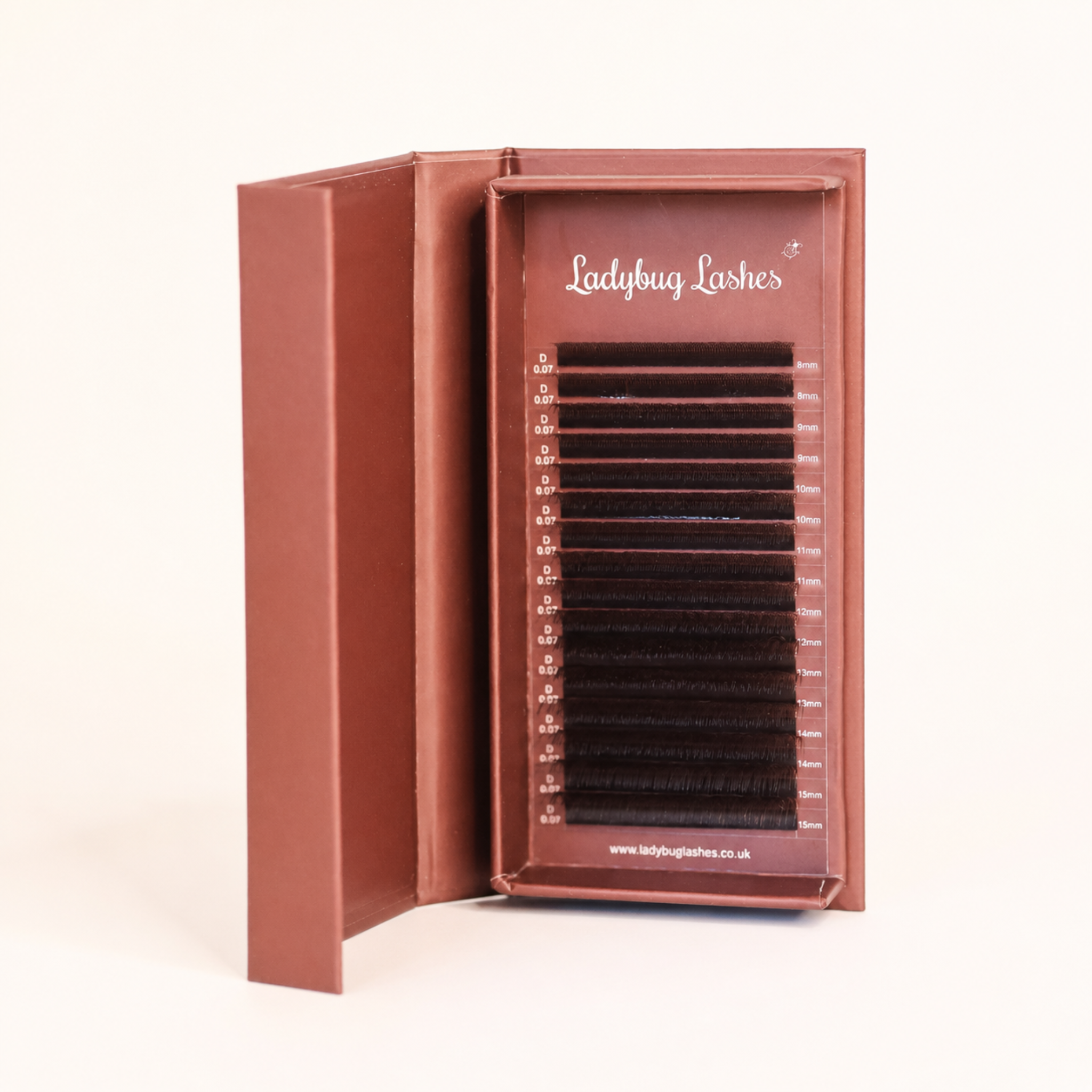 Ladybug Lashes Brown W Lash  tray in open branded box showing full strip of warm brown W lash extensions angled side view