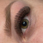 Close-up of completed brown Fairy lash extension set on green eyes showing full dense volume and warm brown tone from front angle