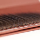 Extreme close-up side angle of brown W lash extensions on Ladybug Lashes tray showing W-shaped curl structure and warm brown tone