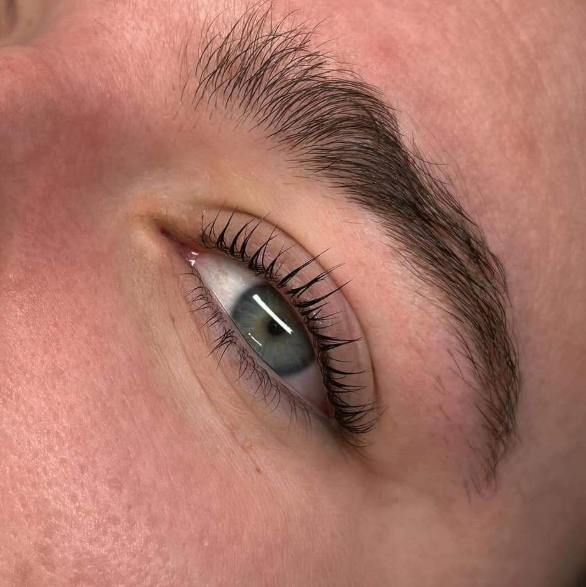 Ladybug Lashes Express Cysteamine System Lash Lift Sachet Kit treatment result extreme close-up showing open grey-green eye from side angle with dramatically lifted and separated natural lashes and defined natural brow with fine lash tips and natural skin texture clearly visible