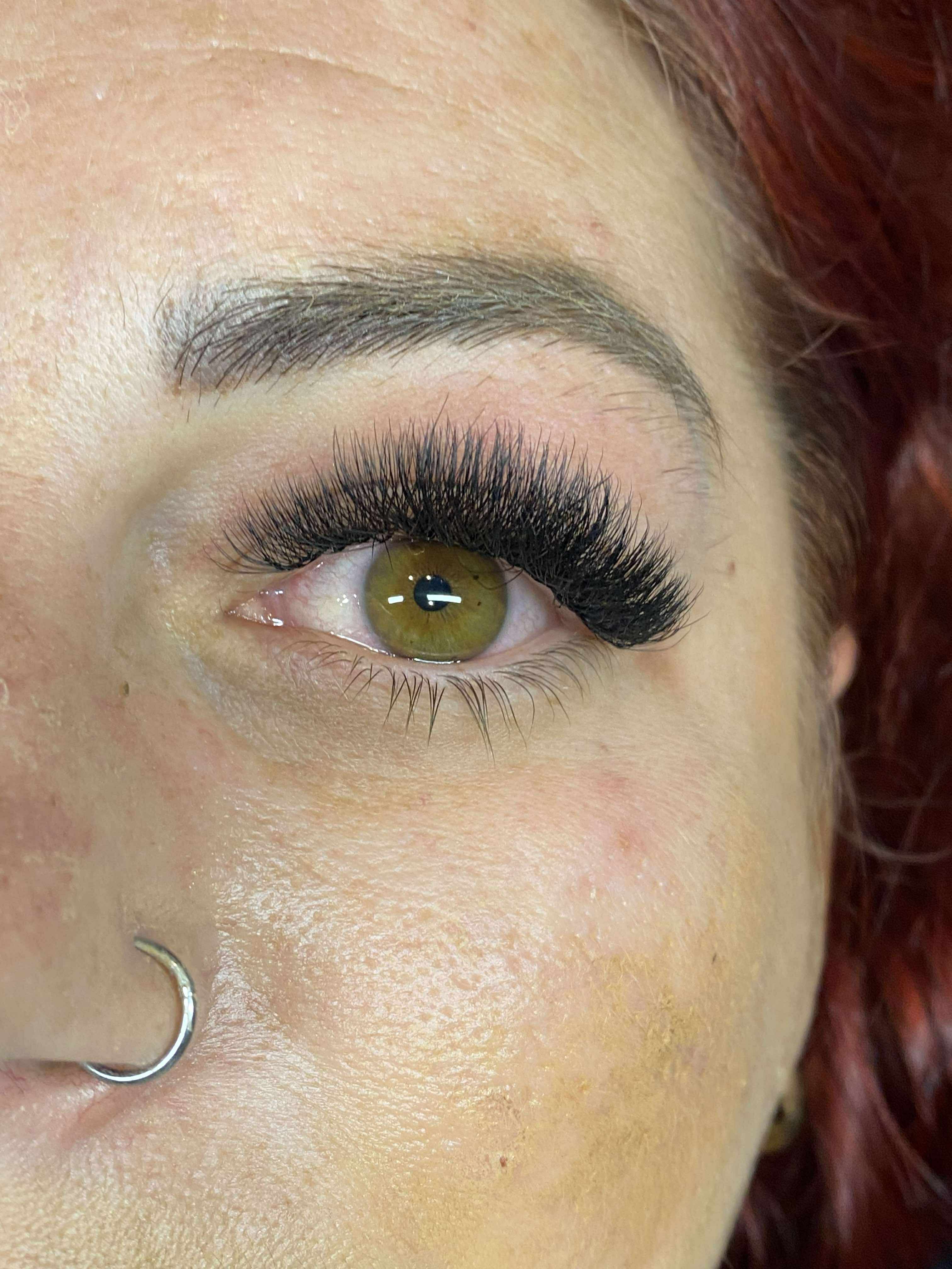 Close-up of a person's eye with false eyelashes and red hair.