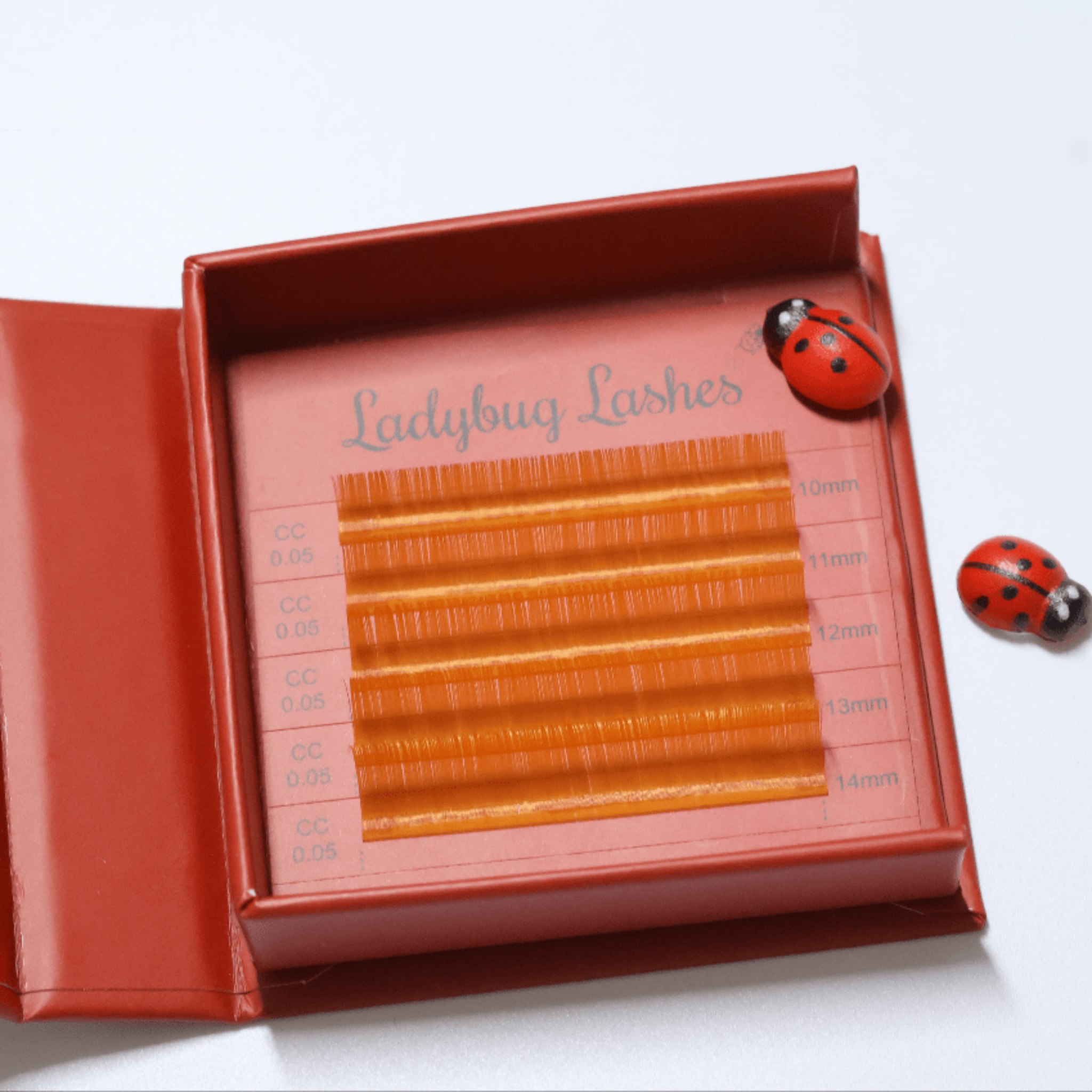 Ladybug Lashes Colour Volume Lashes 0.05mm open tray product shot showing multiple rows of blue and purple volume lash extensions in mixed lengths 10–14mm in a red Ladybug Lashes branded lash tray from diagonal angle on white background