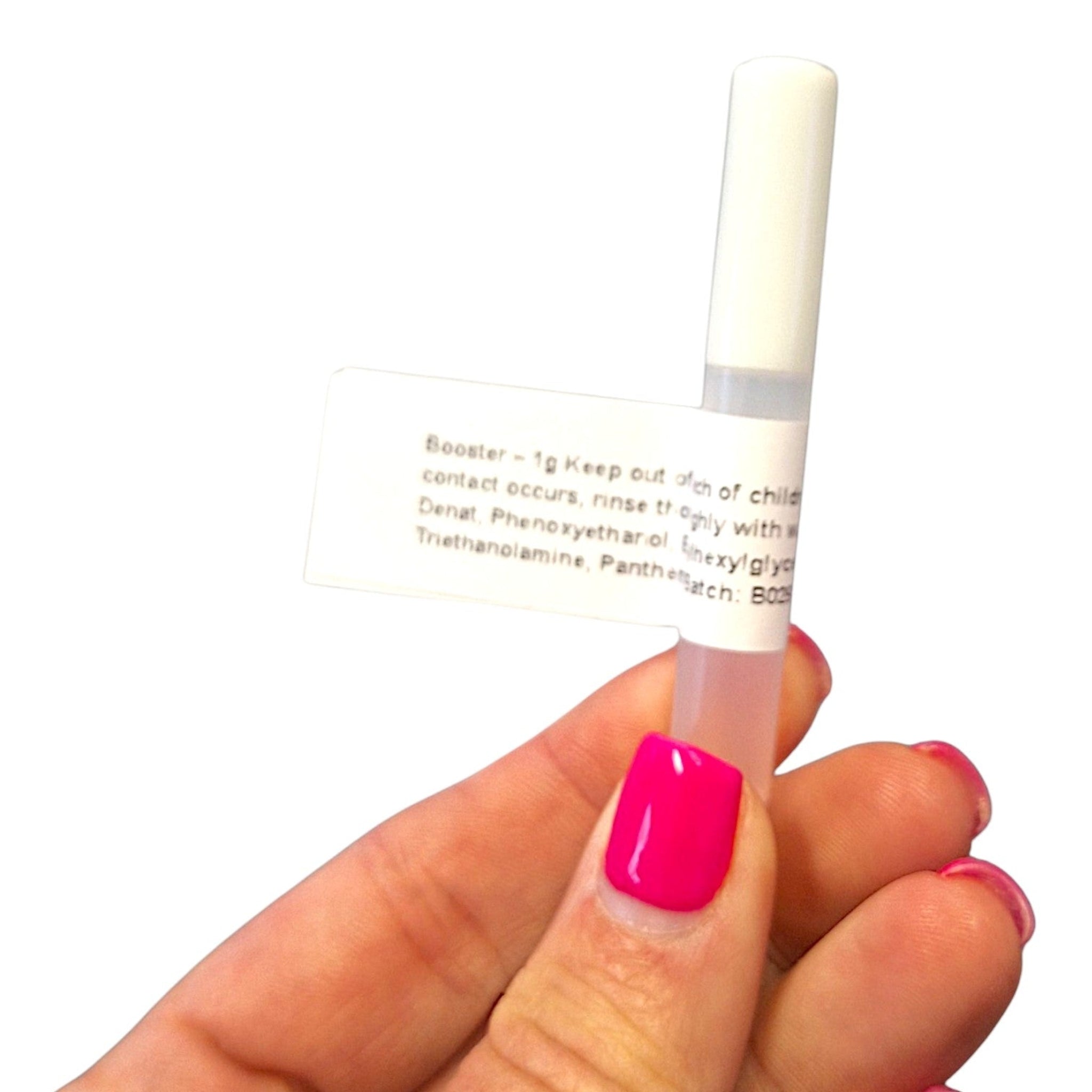 Hand with hot pink nail polish holding a single Ladybug Lashes Retention Booster 1g sample bottle against a white background, showing the white label with "Booster – 1g" text and partial ingredients list including Denat, Phenoxyethanol, Hexylglyc and Triethanolamine, Panthenol with batch number visible