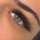 Extreme close-up of completed Ladybug Lashes L curl volume lash extension set on blue-grey eye showing dramatic lift, full upper lash line coverage and wispy separated fan effect