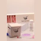 Close-up of Ladybug Lashes Flutter and Frame Express Cysteamine One Two Three airless pump bottles and Powder Lift bottle alongside Ladybug Lashes Hybrid Lash Shields box with pink and purple silicone lash shields in the foreground on a white surface with pink border