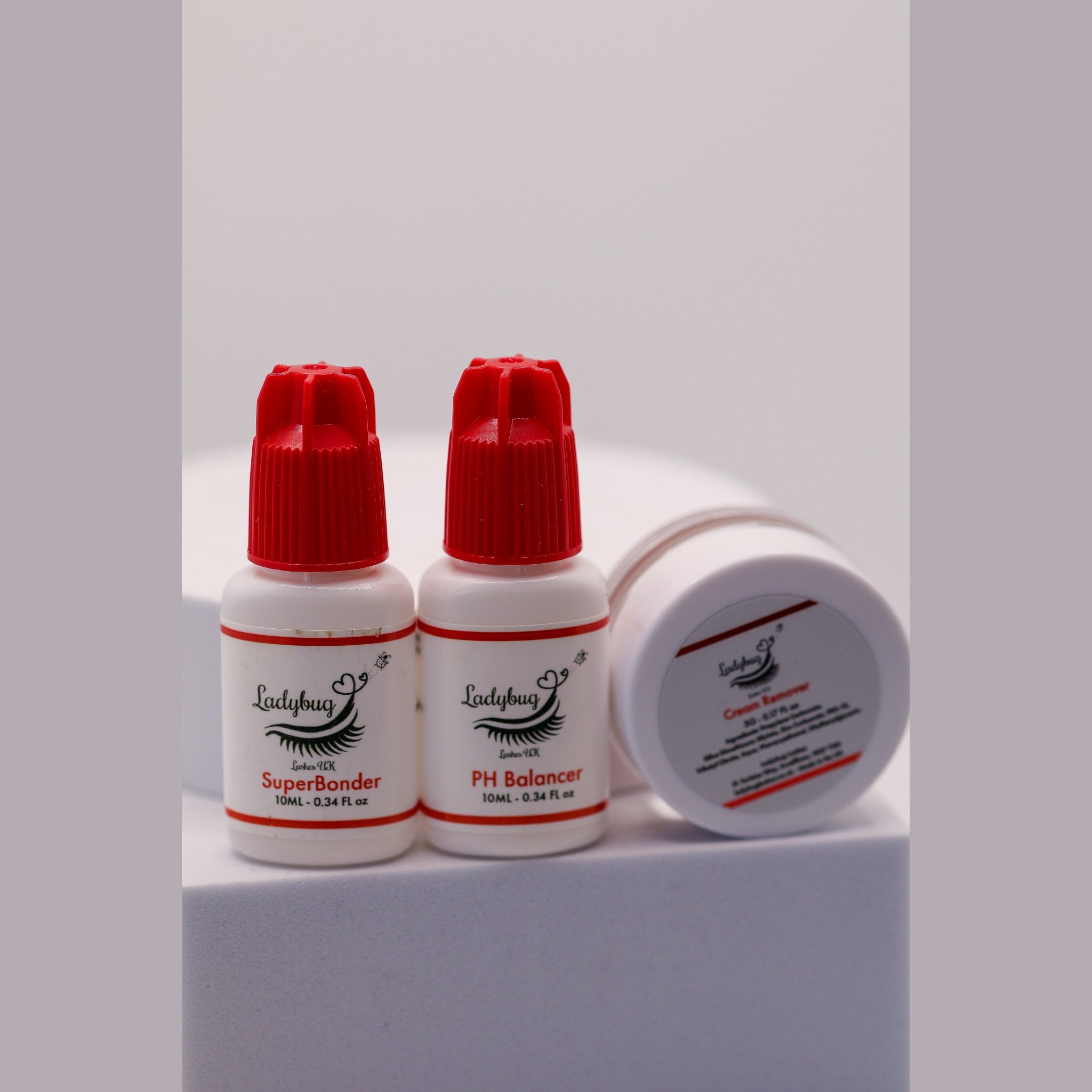 Ladybug Lashes Bonder, pH Balancer and Cream Remover Bundle showing three products on a white background: SuperBonder 10ml clear glass dropper with silver and white pipette cap, PH Balancer 10ml white bottle with red cap, and Cream Remover 5ml white screw-top pot with Ladybug Lashes UK branding and ingredients label visible