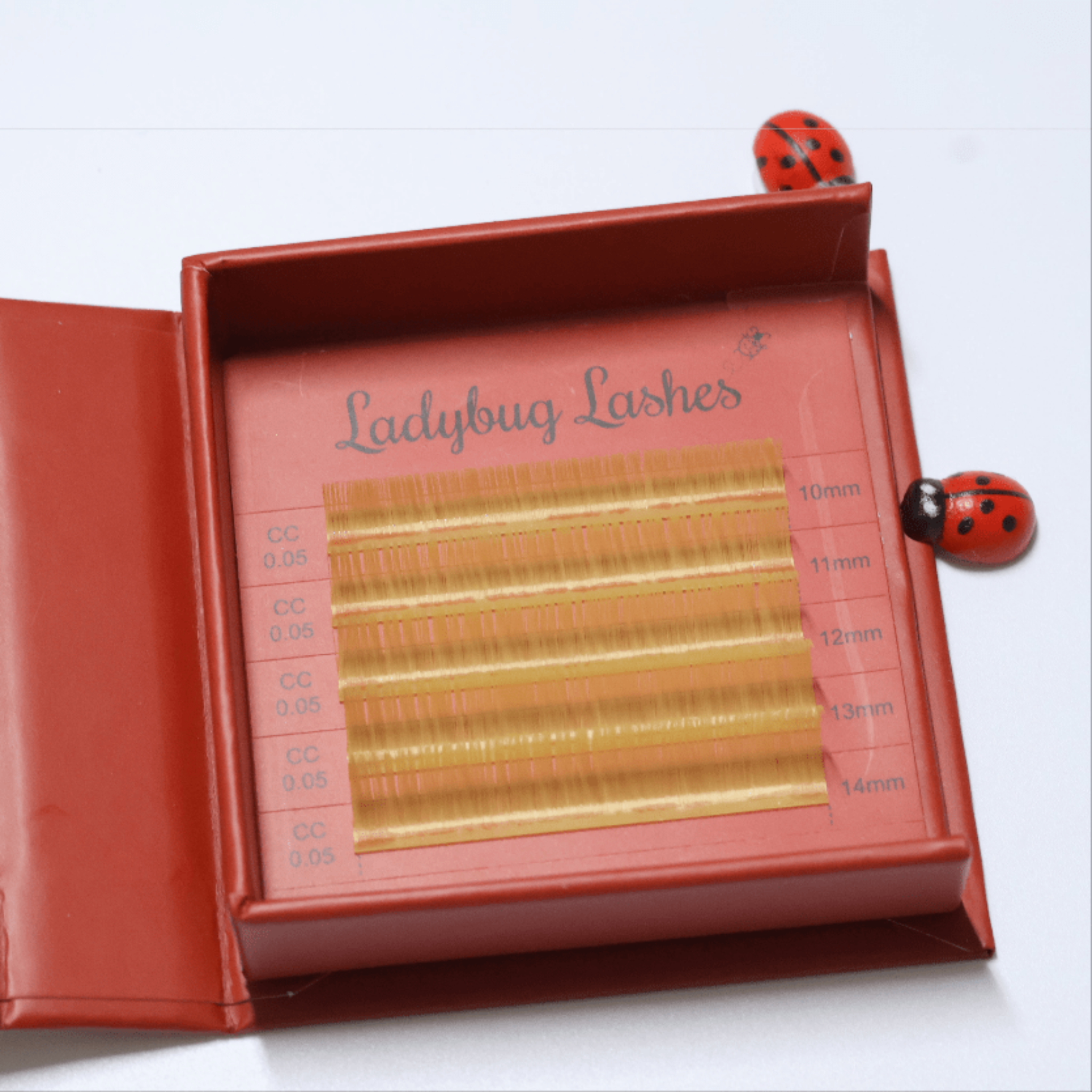 Ladybug Lashes Colour Volume Lashes 0.05mm open tray product shot showing multiple rows of blue and purple volume lash extensions in mixed lengths 10–14mm in a red Ladybug Lashes branded lash tray from diagonal angle on white background